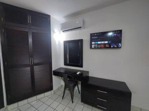 Una habitación con un escritorio y un televisor en la pared. en Villas Cozumel #9, en Cozumel