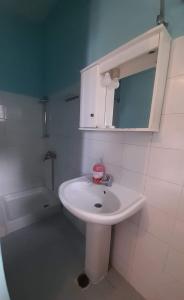 W białej łazience znajduje się umywalka i lustro. w obiekcie Faros w mieście Platamonas