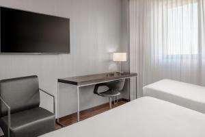 a hotel room with a desk and a bed and a chair at AC Hotel by Marriott Pisa in Pisa