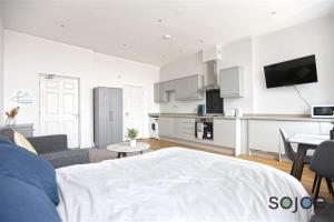 a living room with a bed and a kitchen at Newly refurbished studio with harbour views in Lowestoft