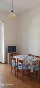 een eetkamer met een tafel en stoelen en een tv bij Family House in Piombino
