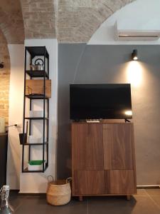 een flatscreen-tv op een houten standaard in een kamer bij Urban79 in Bernalda