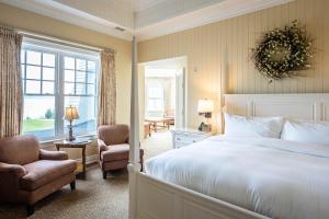 a bedroom with a bed and a chair and a window at The Inn at Cobble Beach in Kemble