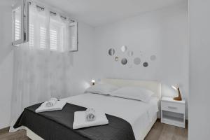 a white bedroom with a bed with two towels on it at Sunny Garden Apartments Ana in Makarska