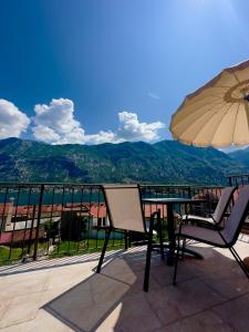 un tavolo con sedie e un ombrellone su un balcone di Lobov view a Kotor (Cattaro)