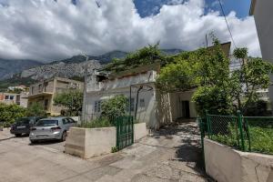 a house with a car parked in a parking lot at Sunny Garden Apartments Ana in Makarska