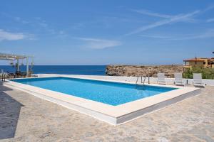 a swimming pool with chairs and the ocean in the background at VORAMAR in Cala en Forcat +33 photos