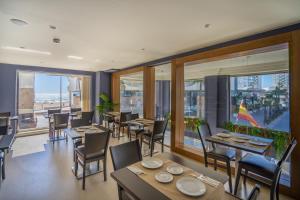 a restaurant with tables and chairs and large windows at Hotel Spa Cádiz Plaza in Cádiz
