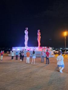 a group of people standing in front of a statue at night at BATUMi ORBI SEA TOWERS SEA WIEV in Batumi