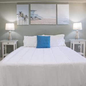 a bedroom with a large white bed with two lamps at Malecon Rooms y Hotel in Santo Domingo