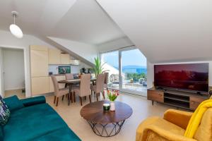 ein Wohnzimmer mit einem Sofa und einem Tisch mit einem TV in der Unterkunft Apartman SMARAGD Živogošće in Živogošće