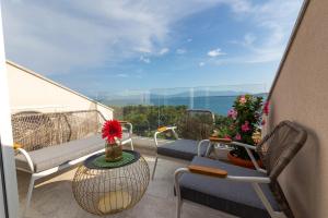 einen Balkon mit Stühlen und einem Tisch mit Meerblick in der Unterkunft Apartman SMARAGD Živogošće in Živogošće