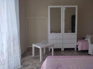 una camera da letto con una cassettiera bianca e un tavolo bianco di Don Aurelio in città ad Acireale