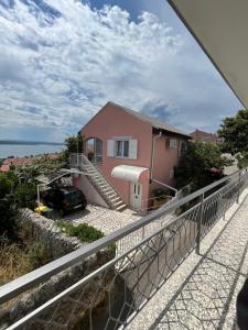 une maison rose avec une voiture garée devant elle dans l'établissement Villa Marija, à Crikvenica