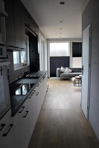 a kitchen with white cabinets and a living room at Ferienhaus Aurora, Sauna, Seeblick, angeln in Twist