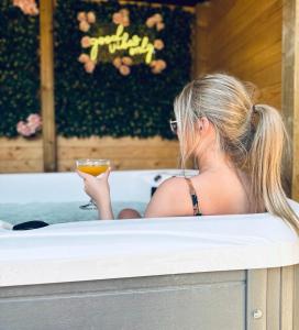 a woman sitting in a bath tub holding a drink at TT Lodges in Stockton-on-Tees