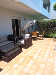 un patio con sofá, mesa y sombrilla en Résidence Al Jazera, en Les Camps