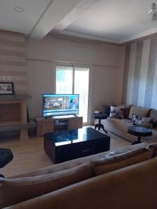 sala de estar con sofá y TV de pantalla plana en Résidence Al Jazera, en Les Camps