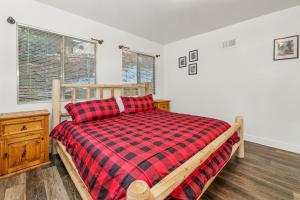 ein Schlafzimmer mit einem Bett mit einer roten karierten Decke in der Unterkunft Family Fun Cabin - Mountain home with Game Room, Hot Tub and Lake Views! in Fawnskin