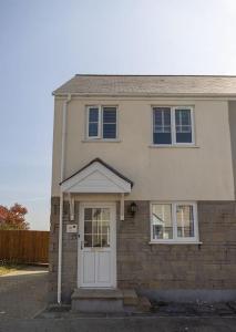 een wit huis met een witte deur en ramen bij The Rosewood, Cornwall. in Roche