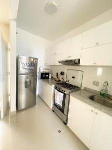 a kitchen with white cabinets and a stainless steel refrigerator at Dpto 3 hab en Piura - GARDEN 360~ in Piura