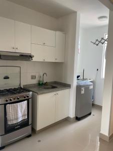 a kitchen with white cabinets and a stove top oven at Dpto 3 hab en Piura - GARDEN 360~ in Piura