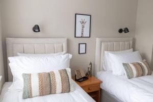 2 bedden in een slaapkamer met witte lakens en kussens bij The Rosewood, Cornwall. in Roche