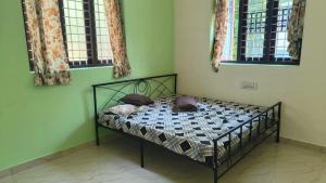 Dragster Homes في Kizhake Chālakudi: سرير في غرفة بجدران خضراء ونوافذ