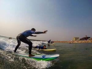 un hombre montando una ola en una tabla de surf en el océano en Casa de Férias_As Oliveiras I en Espinho