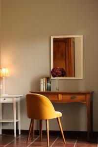 a desk with a yellow chair and a mirror at Cascina del Forte in Torre Pellice