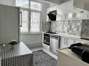 a kitchen with white cabinets and a table in it at Merkezi Konumda Klimalı Aile Dostu Daire in Istanbul