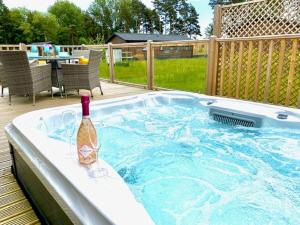 a bottle of wine sitting on the edge of a hot tub at Hollicarrs - Bumblebee Lodge in York