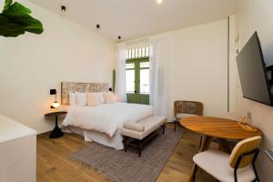 1 dormitorio con 1 cama, mesa y sillas en AmazINN Places Deluxe Estudio Casa Marichu Casco Viejo, en Panamá