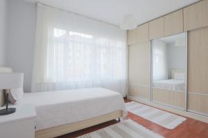 a white bedroom with a bed and a mirror at Merkezi Konumda Klimalı Aile Dostu Daire in Istanbul