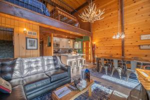 a living room with a leather couch and a kitchen at Fawnskin Family Cabin - Nicely decorated cabin with a lake view and a Foosball Table! in Fawnskin