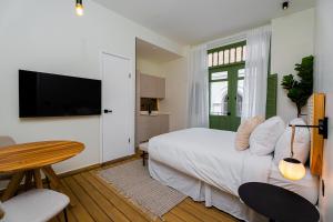Schlafzimmer mit einem Bett, einem Tisch und einem TV in der Unterkunft AmazINN Places Hotel Boutique Casa Marichu in Panama-Stadt