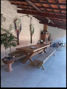 a wooden table and bench in a room with a plant at Recanto do Sossego Saquarema in Saquarema