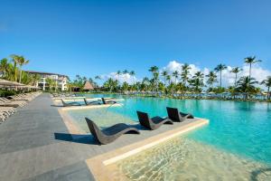 a swimming pool at a resort with chairs in the water at Unique Club at Lopesan Costa Bávaro Resort in Punta Cana