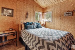 un dormitorio con una cama en una habitación en Forest Edge Retreat - Cozy, log cabin with a wood burning fireplace! Pool Table, Foosball and Darts!, en Big Bear City