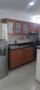 a kitchen with wooden cabinets and a stainless steel refrigerator at Perfecto Apartamento en el Mejor Sector in Cúcuta
