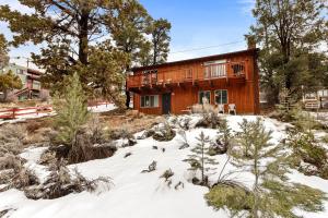 una cabaña de madera en la nieve con árboles en Forest Edge Retreat - Cozy, log cabin with a wood burning fireplace! Pool Table, Foosball and Darts!, en Big Bear City