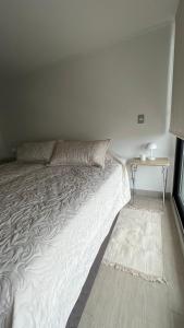 ein weißes Bett in einem Zimmer mit einem Tisch in der Unterkunft Departamento entero, cerca Plaza Egaña, Estacionamiento gratis in Santiago
