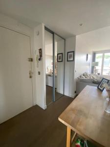 a living room with a wooden table and a door at Bel appartement cosy proche de Paris in Saint-Maur-des-Fossés