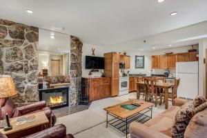 sala de estar con pared de piedra y cocina con chimenea. en Laurelwood Condominiums 408 en Snowmass Village