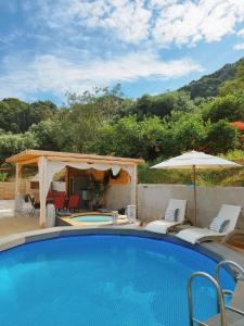 a swimming pool with chairs and an umbrella at Country House DAFNI in Vasilikos