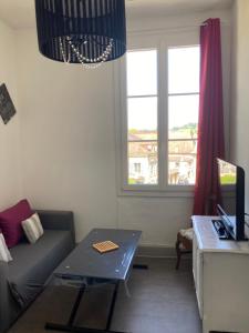 sala de estar con sofá, mesa y ventana en Centre médiéval Sarlat en Sarlat-la-Canéda