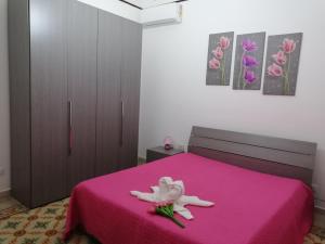 ein Schlafzimmer mit einem rosa Bett mit einer rosa Decke in der Unterkunft Tulipano in Trapani