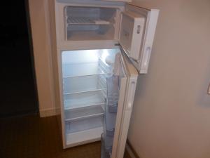 einem leeren Kühlschrank mit offener Tür und einer Mikrowelle in der Unterkunft Apartmán u zámku in Smečno