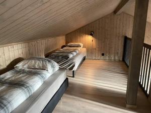 two beds in a room with wooden walls at Skaidi Logde- near salomon river and golf course in Hammerfest