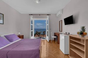 a bedroom with a purple bed and a view of the ocean at Beachfront Rooms Ana in Tučepi